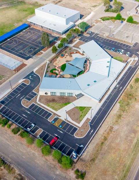 Aerial view of a commercial school complex with shaded play area, basketball courts and parking