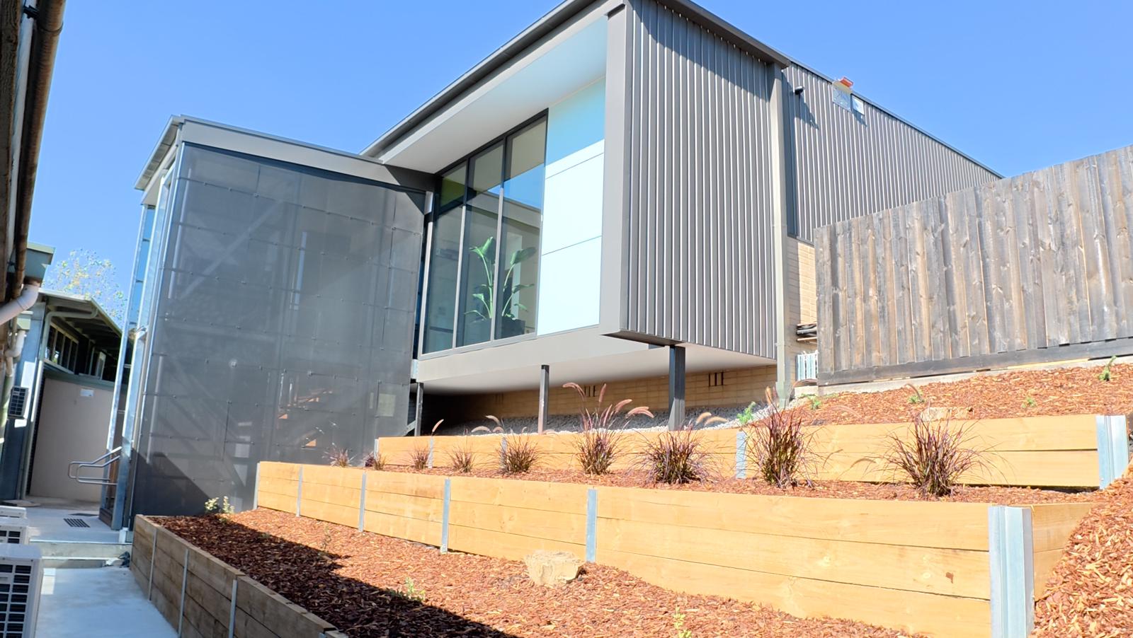 Tiered timber retaining beds and new plantings against a modern clad commercial building