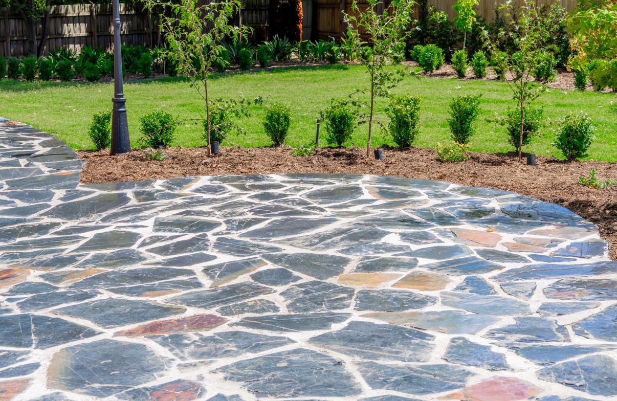 Crazy paving terrace edged with clipped hedges and a Victorian lamp post