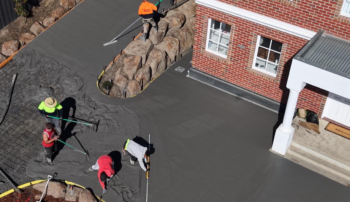 Crew screeding wet concrete during a driveway pour at the Sunbury estate