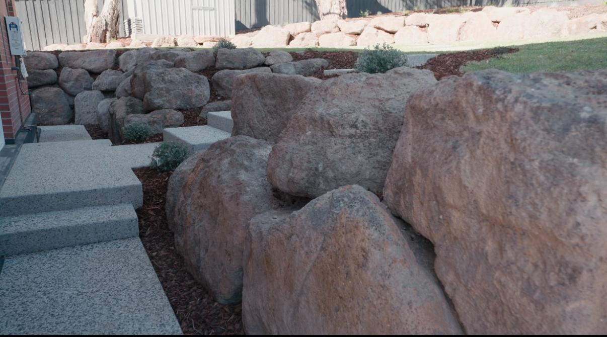 Boulder retaining wall with side path and integrated steps at the Sunbury estate